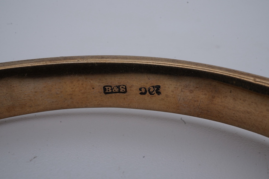 A gold bangle, engraved with scrolled decoration, inner circumference approximately 21.5cm, stamped 9CT, gross weight approximately 10 grams